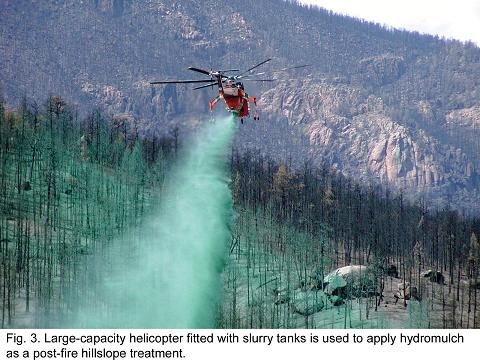 Fig. 3 -- Large capacity helicopter fitted with slurry tanks is used to apply hydromulch as a post-fire hillslope treatment.